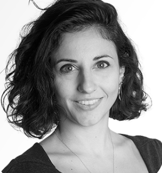 A portrait of a woman with curly hair, smiling against a plain background.